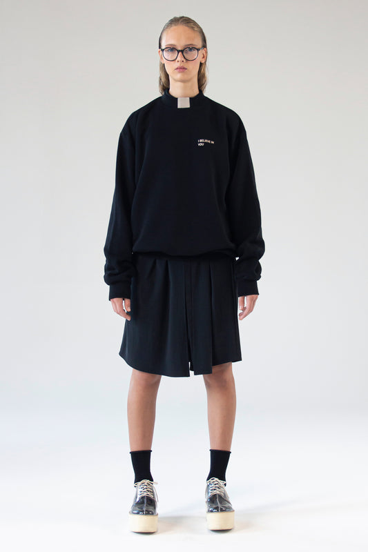 Unisex black sweater ‘I Believe In You’ by One Wolf, front view on model with relaxed fit and subtle silk print text.