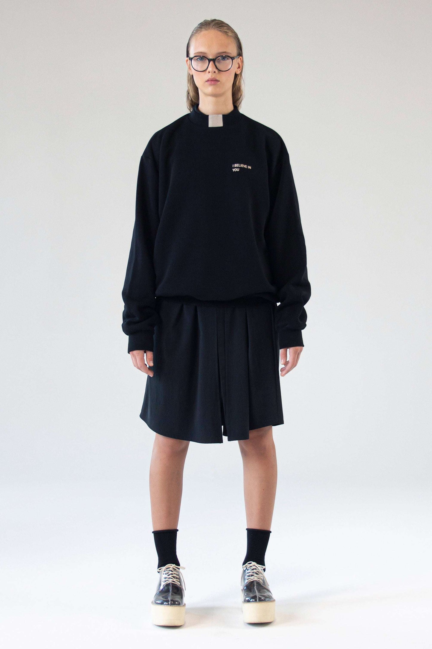 Unisex black sweater ‘I Believe In You’ by One Wolf, front view on model with relaxed fit and subtle silk print text.